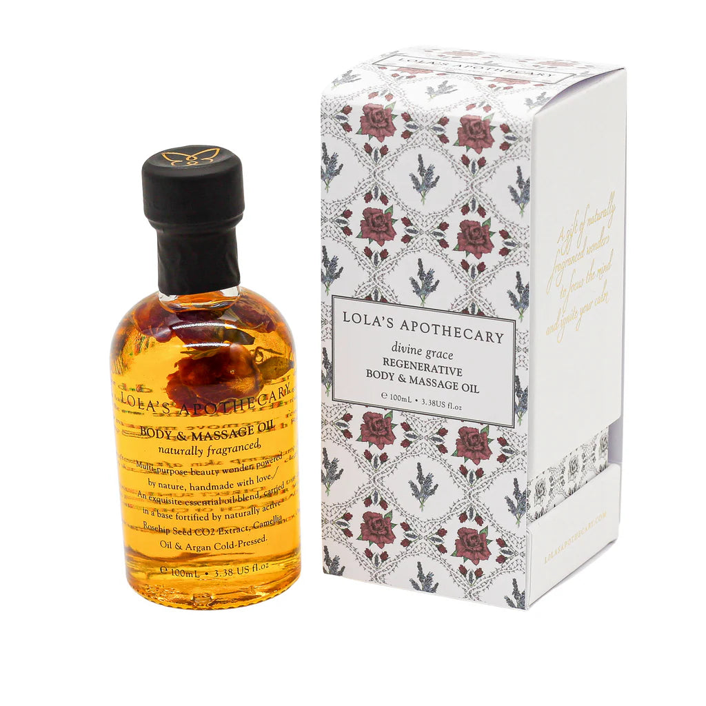 A bottle of "Divine Grace" regenerative body massage oil next to a floral gif box