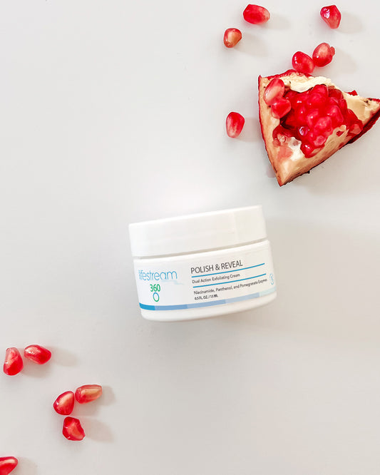 Travel size jar of exfoliating cream with pomegranate seeds on a light background