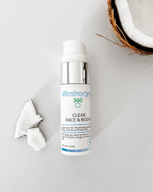 Travel size bottle of face and body wash on a light gray background with coconut pieces