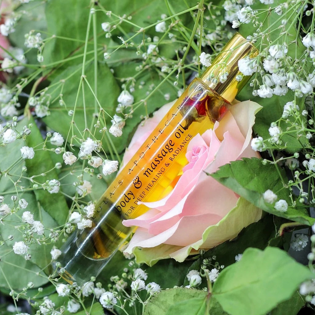 A roll-on bottle of "Divine Grace" perfume oil nestled on a rose and white flowers