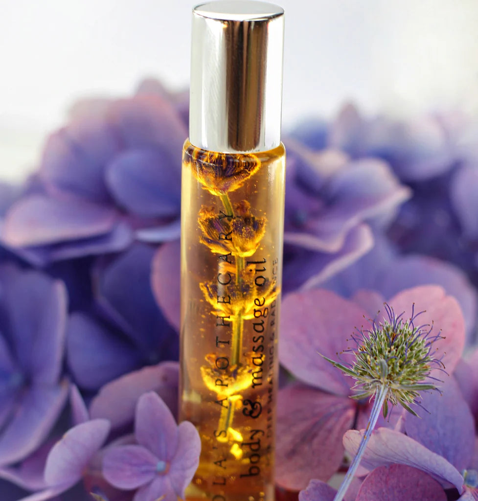 A roll-on bottle of "Sweet Lullaby" perfume oil with purple flowers  around it
