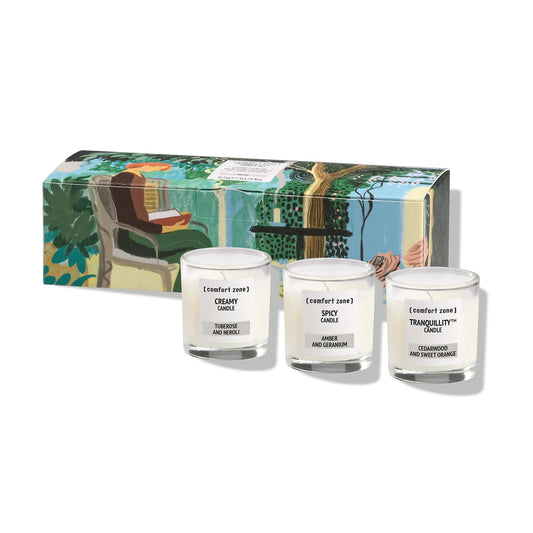 Three Comfort Zone candles in front of a decorative gift box on a white background